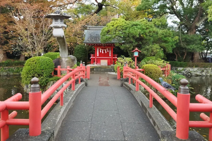 Vermilion bridge leading to the small island shrine of Benzaiten in the pond at Mishima Taisha